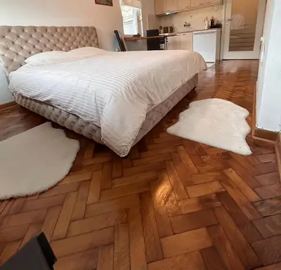 a bedroom with a bed and two rugs on the floor at Cozy with parking in Zemun