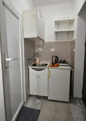 a small kitchen with white cabinets and a sink at Studio Sky in Belgrade