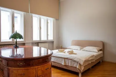 a bedroom with a bed with a table and windows at King Peter Apartment in Belgrade
