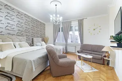 a bedroom with a large bed and a chair at Illusion Downtown Apartment in Belgrade