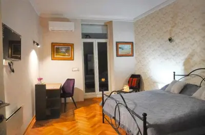 a bedroom with a bed and a table and a desk at Gracia apartment in Belgrade