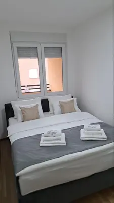 a large white bed in a room with two windows at Maja 2 in Ruma