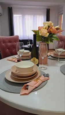 a table with plates and glasses and a vase of flowers at Maja 2 in Ruma