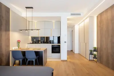 a kitchen with white cabinets and a island with blue chairs at Leo Urban Lux, comfort - Central Stay, Free Garage in Belgrade