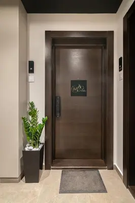 a wooden elevator door in a lobby with a potted plant at Melody Apartment in Novi Beograd