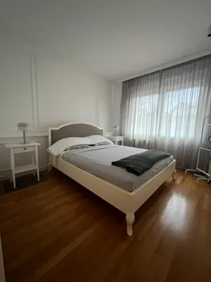 a white bedroom with a bed and a window at Nevski Apartment in Belgrade