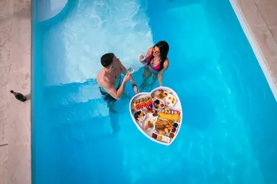 a man and a woman in the water at a pool at The Crown Pool Villa in Belgrade