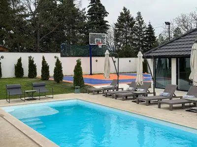 a swimming pool with chairs and a basketball hoop at The Crown Pool Villa in Belgrade