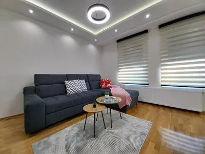 a living room with a blue couch and a table at Lider Lux Apartman in Arandjelovac