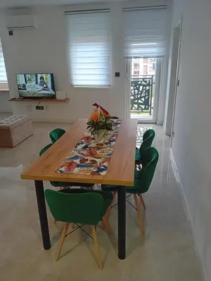 a dining room table with green chairs around it at Ruma Deluxe 90m2 in Ruma