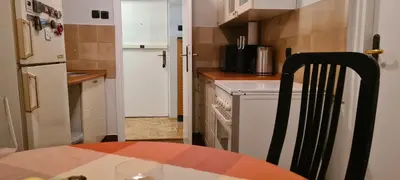a kitchen with a table and a white refrigerator at Grey apartment Novi Beograd in Belgrade