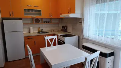 a kitchen with orange cabinets and a white table and chairs at Apartman Anja in Velika Granice
