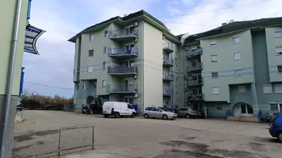 a large apartment building with cars parked in a parking lot at Apartman Anja in Velika Granice