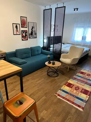 a living room with a blue couch and a bed at Sleep&Fly Belgrade in Ledine