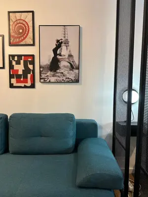 a living room with a blue couch and pictures on the wall at Sleep&Fly Belgrade in Ledine