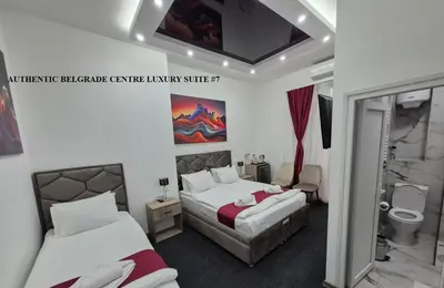 a hotel room with two beds and a bathroom at Authentic Belgrade Centre Suites with Patios in Courtyard for Smokers in Belgrade