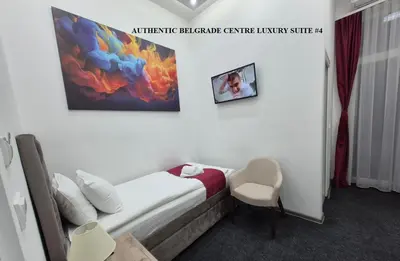 a hotel room with a bed and a chair at Authentic Belgrade Centre Suites with Patios in Courtyard for Smokers in Belgrade