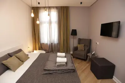 a bedroom with a bed and a couch and a tv at Moment Boutique Apartments in Belgrade