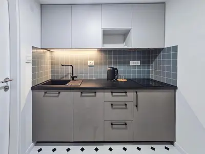 a kitchen with white cabinets and a black counter top at City life in Belgrade