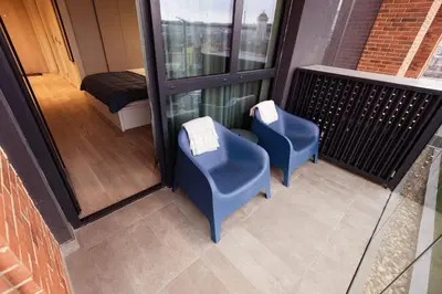a balcony with two blue chairs and a bed at Galerija Libera in Belgrade