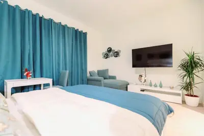 a bedroom with blue curtains and a bed and a tv at Galerija Libera in Belgrade