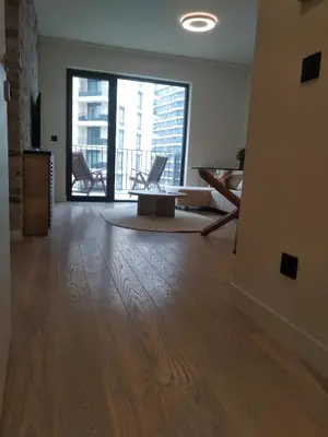 a living room with a wooden floor and a large window at BW Premium 5th Symphony in Belgrade