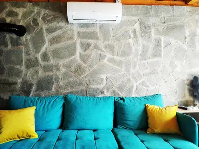 a blue couch with yellow pillows in front of a stone wall at Imanje in Arandjelovac