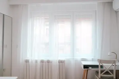 a window with white curtains in a room with a desk at Sweet House Skadar Lux in Belgrade