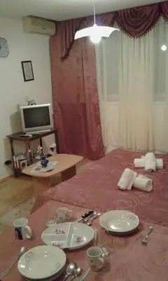 a living room with a table with plates and a television at Apartment Daca Stan na dan in Belgrade