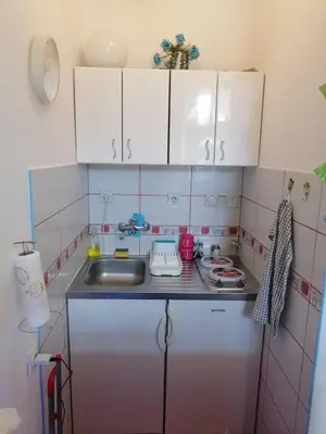 a small kitchen with white cabinets and a sink at Small low cost studio in Belgrade