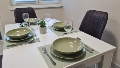 a table with plates and wine glasses on it at Apartman Enjoy Arandjelovac in Arandjelovac