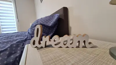 a wooden sign that reads homework on a bed at Apartman Enjoy Arandjelovac in Arandjelovac