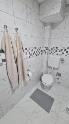 a white bathroom with a toilet and towels at Apartman Enjoy Arandjelovac in Arandjelovac