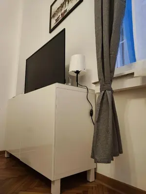 a tv on top of a white cabinet with a lamp at Parlament City Center in Belgrade