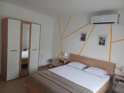 a bedroom with a bed and a wall with a fan at Kućica LaMa-Кућица ЛаМа in Mali Mokri Lug