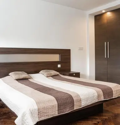 a bedroom with a large bed with a wooden headboard at KAN Suites 1 in Belgrade