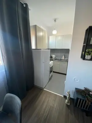a kitchen with white cabinets and a chair in a room at Apartman Felix in Zvezdara