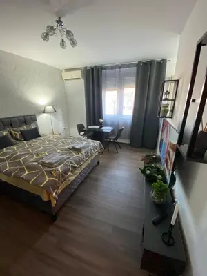 a bedroom with a bed and a living room with a table at Apartman Felix in Zvezdara
