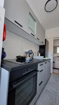 a kitchen with a black stove and white cabinets at CashIN apartment in Belgrade