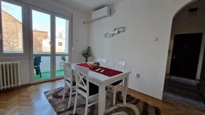 a white dining room with a table and chairs at CashIN apartment in Belgrade