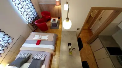 a small attic bedroom with two beds and a red chair at Atos in Novi Beograd