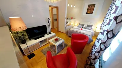 a living room with red chairs and a television at Atos in Novi Beograd