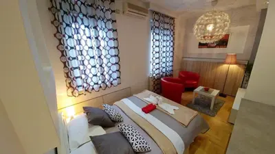 a bedroom with a large bed and a red chair at Atos in Novi Beograd