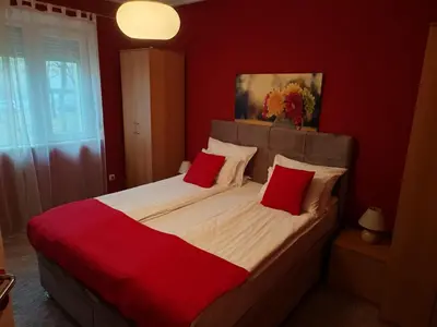 a red bedroom with a large bed with two red pillows at Stadion apartman in Belgrade