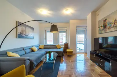 a living room with a blue couch and a tv at Panorama Central - Vračar Apartment in Belgrade