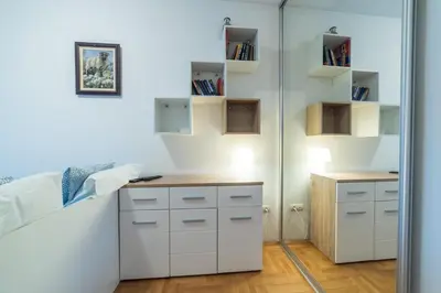 a bedroom with a closet with white cabinets and a desk at Panorama Central - Vračar Apartment in Belgrade