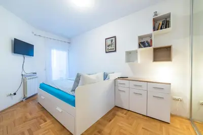 a white bedroom with a bed and a desk at Panorama Central - Vračar Apartment in Belgrade