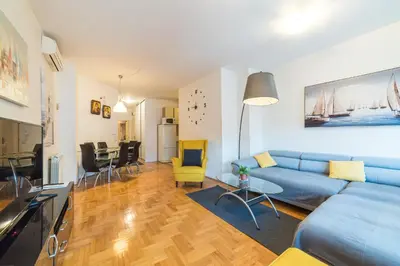 a living room with a blue couch and a kitchen at Panorama Central - Vračar Apartment in Belgrade
