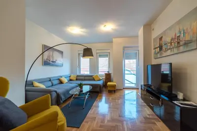 a living room with a blue couch and a tv at Panorama Central - Vračar Apartment in Belgrade
