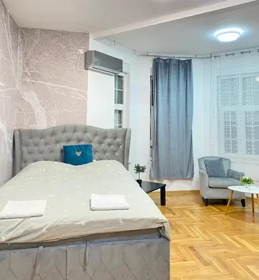 a bedroom with a large bed and a chair at Urban Aura Belgrade in Belgrade